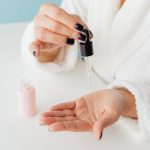 Woman applying skincare serum from a dropper
