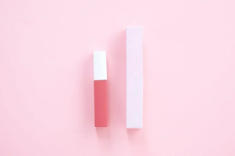 Pink lip gloss and plain packaging on a pastel pink background