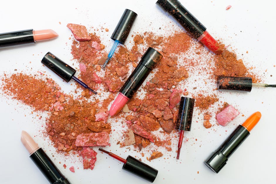 Colorful lipsticks and makeup powders arranged on a white surface